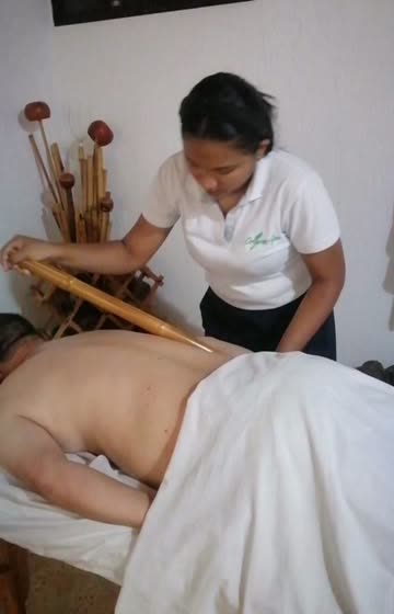 Terapeuta deslizando una caña de bambú sobre la espalda de un cliente