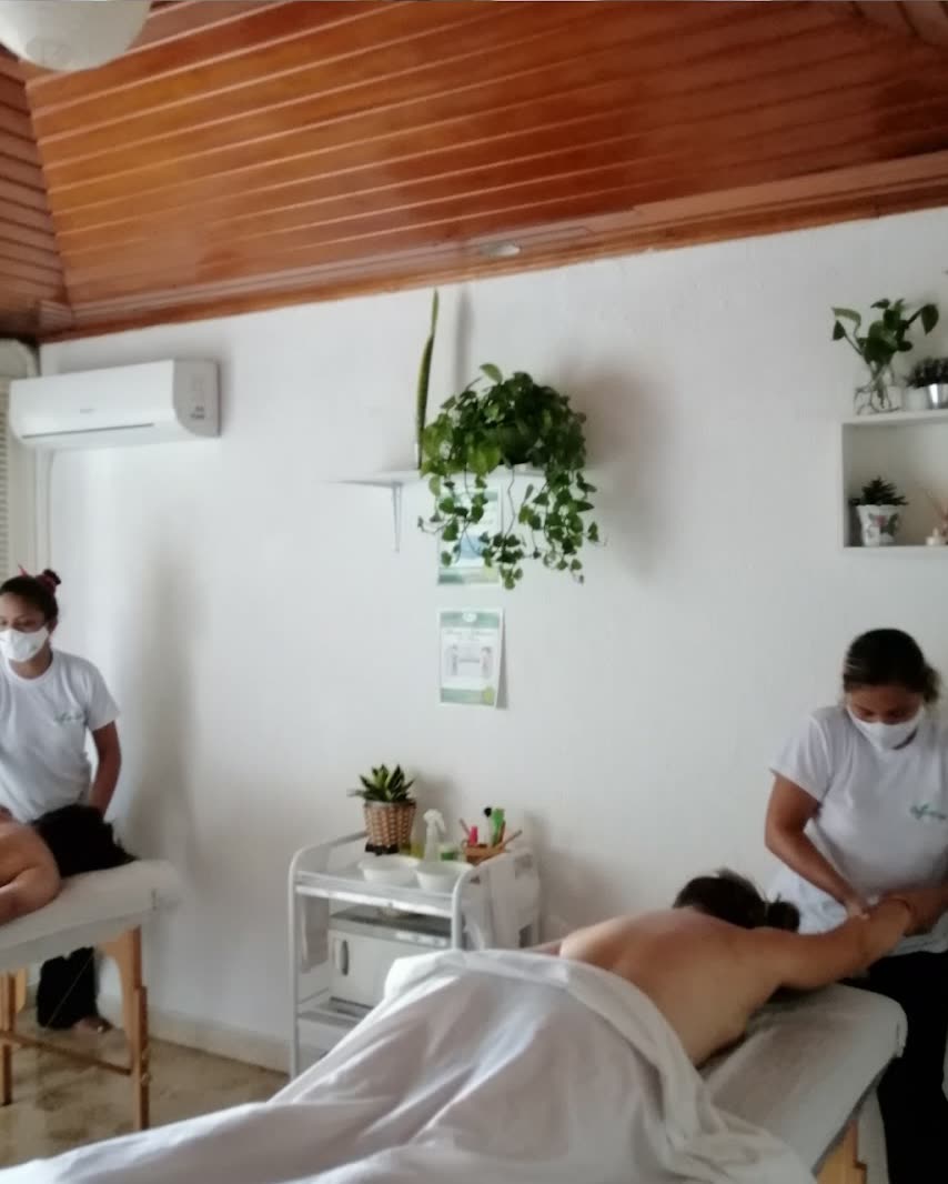 Cabina de Organic Spa con techo de madera, matas colgantes y dos terapeutas dando masaje