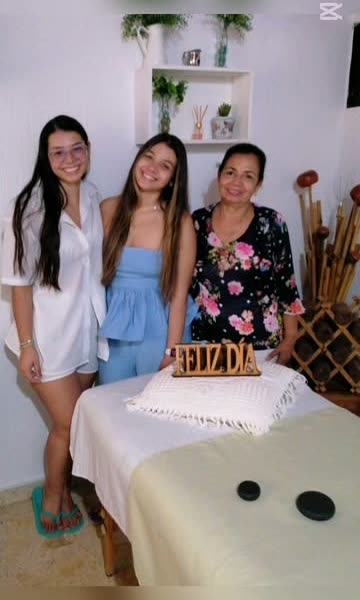 Tres clientas celebrando junto a la camilla con el letrero Feliz día
